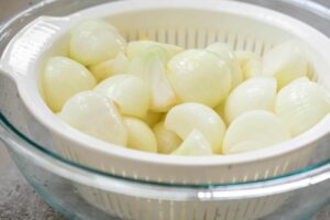 draining salted onion wedges in a white strainer