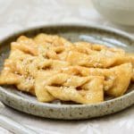 Korean twisted ginger cookies topped with chopped pine nuts with a cup of tea