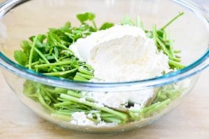Flour over cut Korean watercress in a pyrex bowl