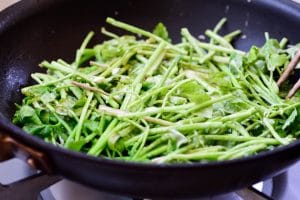 Minari pancake being fried up in a nonstick pan