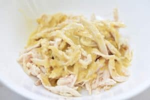 Mixing shredded chicken with pine nut dressing